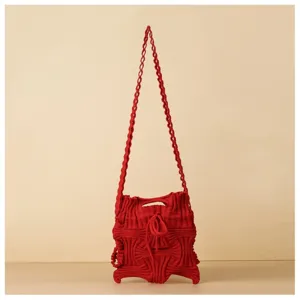Detailed macro view of a unique red knitted crossbody bag featuring pleated woven texture