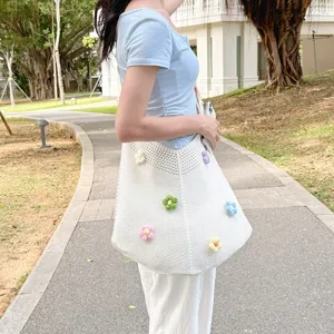 Close-up of the stylish white knitted shoulder bag featuring colorful crochet flower details.