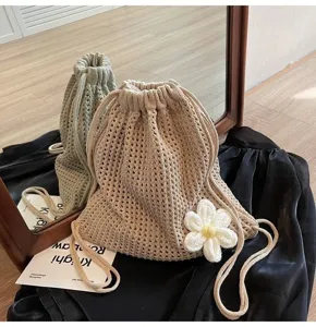 Detalle de una mochila de punto beige con una gran flor blanca de ganchillo decorativa