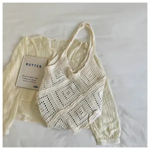 Close-up of bohemian hollow-out knitted tote bag with intricate cream woven textures.