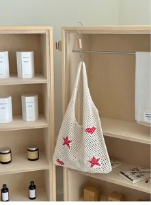 Detailed view of a white crochet tote bag with red heart and star patterns in a wooden closet