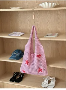 Macro view of pink mesh knit tote bag with red heart pattern in a boutique setting