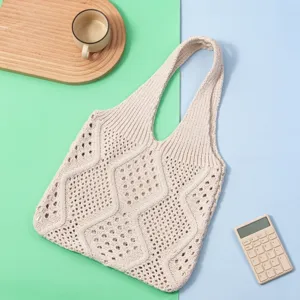 Detalle de bolso tote de punto calado beige con elegante patrón de diamantes y textura.