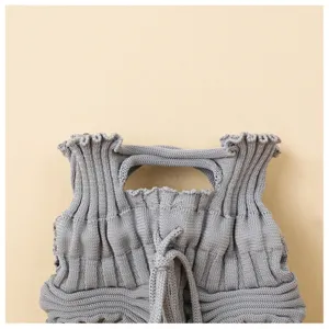 Close-up of grey knitted pleated handbag featuring ruffled edge and woven handle details.