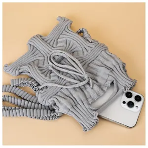 Detailed view of grey knitted pleated mini crossbody phone bag with smartphone inside
