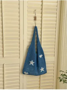 Blue hollow-out knitted tote bag with white star and heart patterns hanging on a door