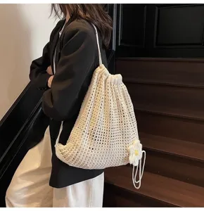 Vista detallada de la mochila de punto blanco con cordón y detalle de flor decorativa.