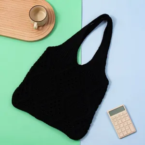 Vista detallada del bolso tote de punto negro con un patrón de tejido hueco de rombos