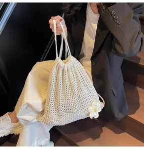 Modelo con bolsa de punto blanca y detalle de flor de ganchillo en escaleras