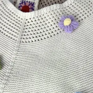 Detailed shot of a casual handmade crochet knit shoulder bag with cute floral decorations.