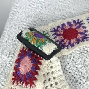 Close-up detail shot of colorful crochet knitted shoulder bag strap with adjustable black buckle.