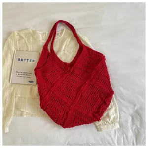 Red knitted hollow-out beach tote bag with bohemian style on casual clothing background