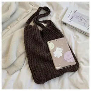 Detailed view of a dark brown knitted tote bag with textured weave on a cozy bed setting