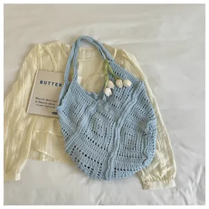 Detailed view of a light blue hollow knitted beach tote with tulip floral decoration