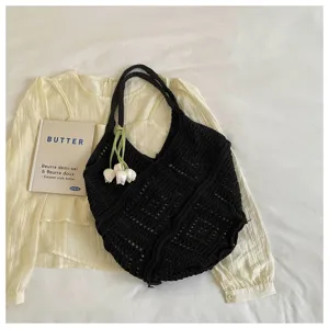 Macro view of black hollow-out crochet tote bag with tulip floral charm detail