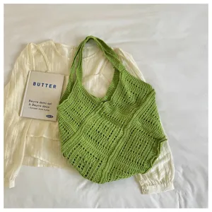 Green bohemian hollow crochet tote bag shown with lifestyle props on white fabric