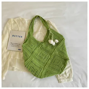 Detailed view of green bohemian knitted tote bag with hollow-out pattern and tulip charm