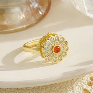 Close-up of elegant gold rotating flower ring with orange gemstone and pavé petals