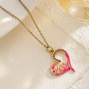 Close-up detail of a gold heart-shaped MOM pendant with pink enamel and purple crystals
