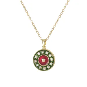 Rotating gold-plated evil eye pendant necklace with red and green enamel accents.