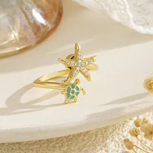 Detail shot of a gold starfish and turtle rotating open ring with sparkling zircons