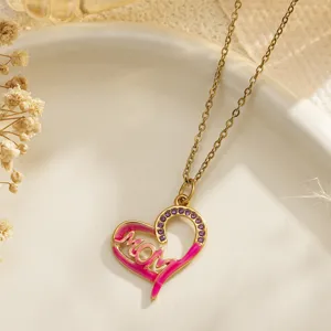 Detail of a gold heart pendant necklace with pink enamel and 'MOM' engraved lettering