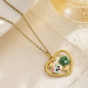 Close-up detail of a gold heart pendant featuring adorable enamel cat figures and charms