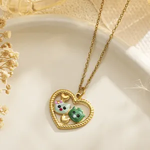 Detailed view of an enamel kitten heart pendant necklace displayed on a ceramic plate with dried flowers