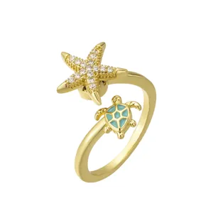 Gold plated spinner ring featuring a CZ encrusted starfish and blue enamel sea turtle charm