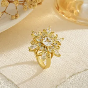 Gros plan d'une bague fleurie dorée avec micro-pavé de zircons et une pierre centrale carrée