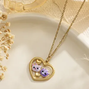 Macro detail of a gold heart pendant necklace featuring two cute purple enamel cat figures