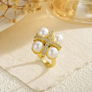 Detailed macro view of a gold open ring featuring four pearls and zircon-set cross