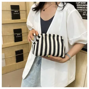 Détail montrant une pochette nuage à rayures noires et blanches tenue par un mannequin