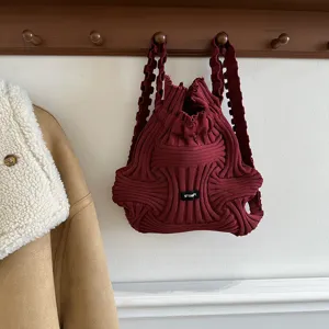 Close-up of burgundy knitted backpack showing intricate woven texture and brand label