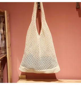Vista dettagliata di una borsa tote in rete all'uncinetto avorio con maglia