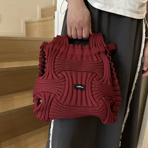 Detailed view of a stylish burgundy knitted woven handbag with a pleated texture