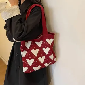 Nahaufnahme einer roten Stricktasche mit weißen Herzmustern auf der Schulter eines Models