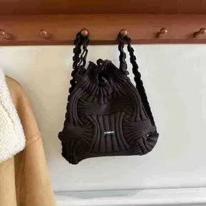 Close-up of a stylish black knitted woven backpack hanging on a wooden wall coat rack