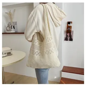 Detail view of a cream white crochet knit tote bag carried by a model in casual style