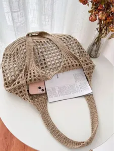 Détail d'un grand sac cabas en maille crochet beige contenant téléphone et magazine