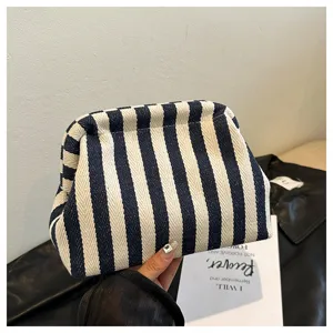Vue détaillée d'une pochette nuage en tissu à rayures bleues et blanches tenue à la main.