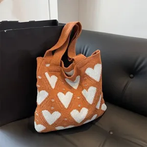 Orangefarbene Strick-Einkaufstasche mit weißem Herzmuster in einer Lifestyle-Umgebung