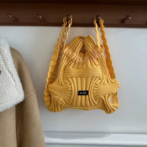 Niche yellow knitted backpack with unique woven texture hanging on wooden rack