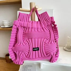 Detail view of bright pink pleated knitted handbag featuring unique 3D textured design.