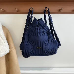 Detail view of navy blue knitted woven backpack with unique structural design hanging on a rack