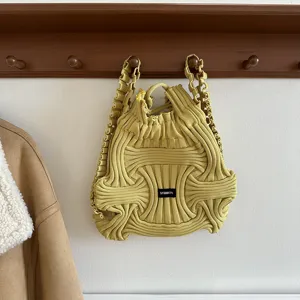 Detail view of yellow knitted woven handbag hanging on a rustic wooden wall rack