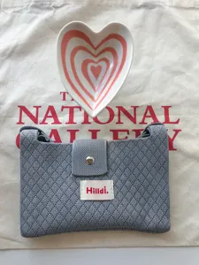 Grey knitted crossbody phone bag detail, soft texture and metal snap closure for daily use.
