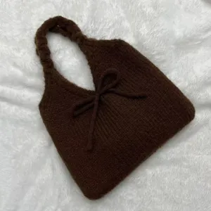 Detailed view of a brown knitted tote bag with a bow detail and soft furry texture