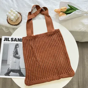 Brown knitted mesh tote bag in a cozy lifestyle setting with floral and candle props