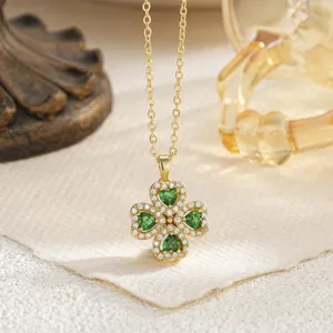 Macro detail of a golden palace style four-leaf clover pendant with green heart gems